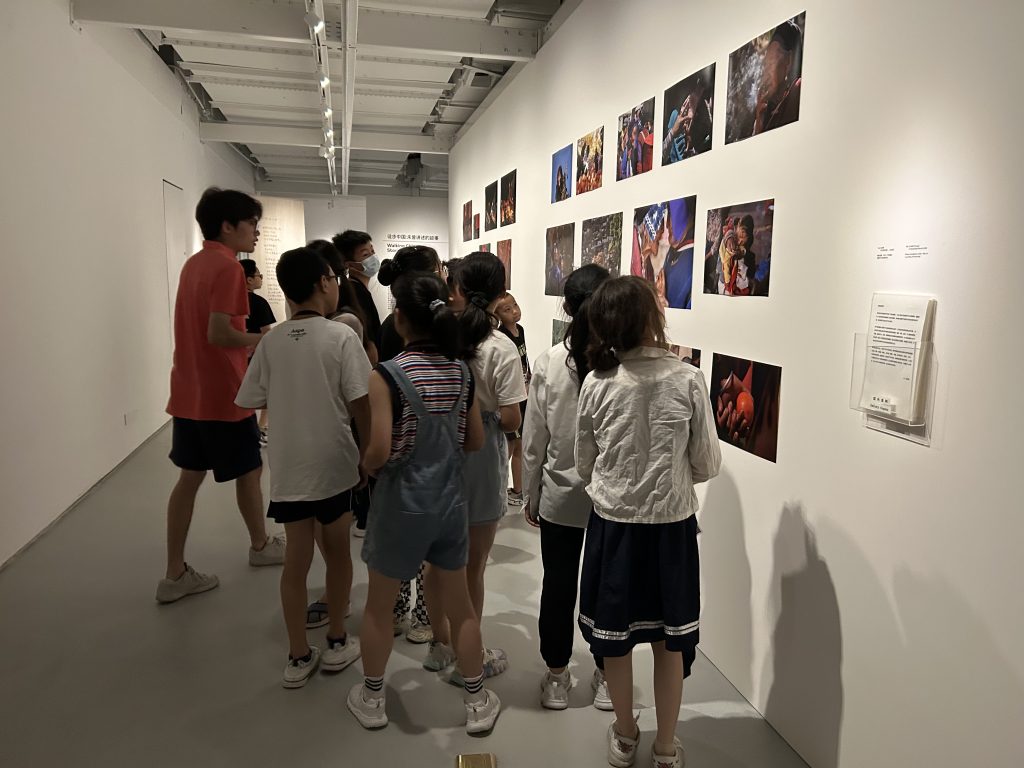 A group of students look at photographs displayed on a museum wall.